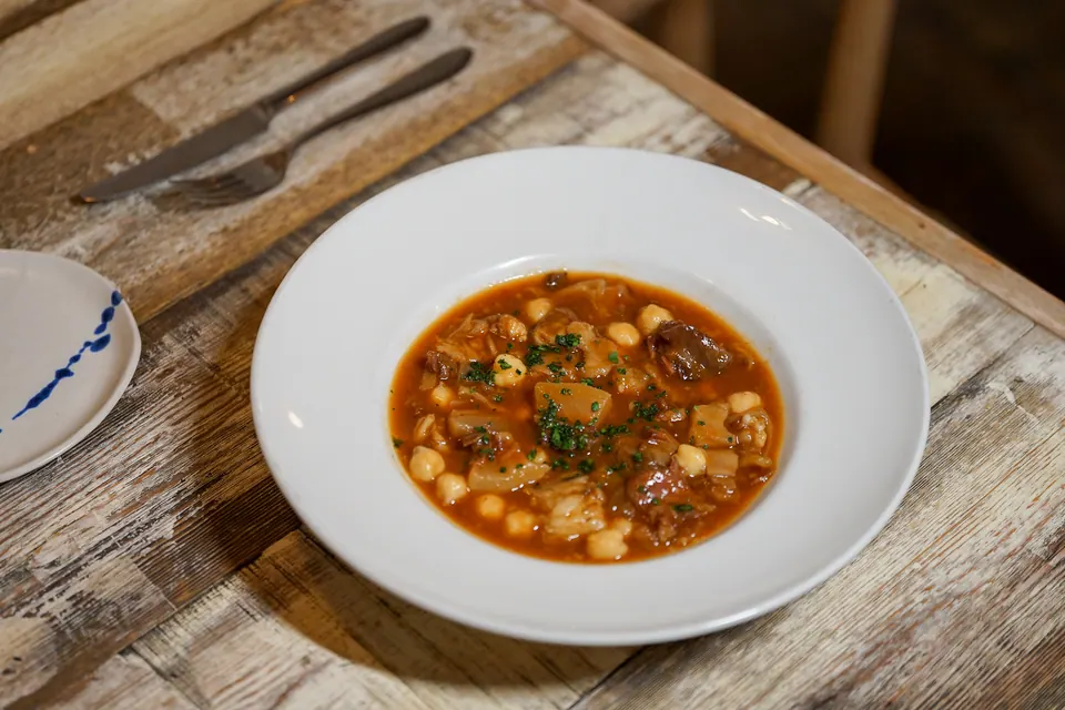 Guiso de cuchara con garbanzos y carne servido en plato hondo