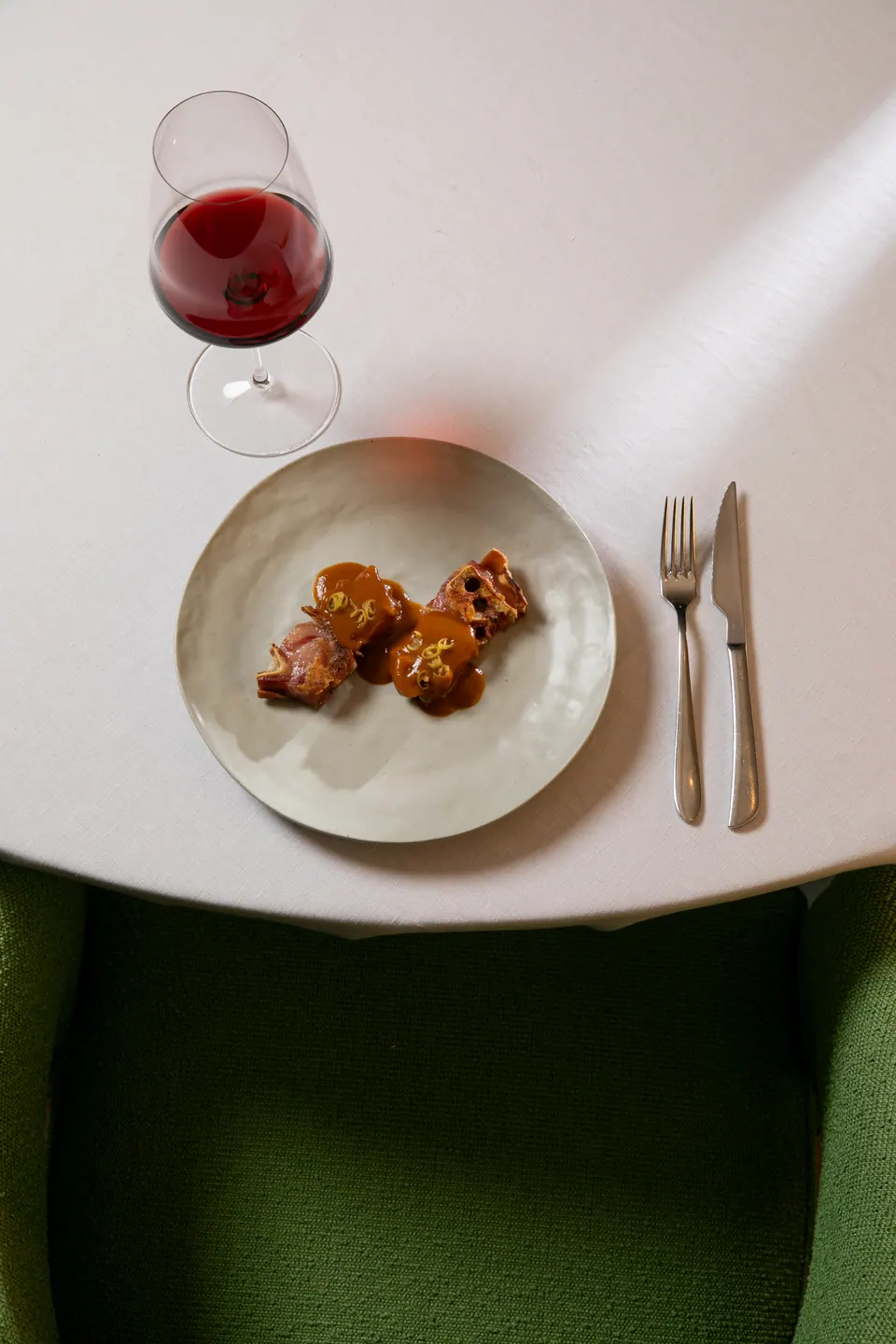 Plato de carne con salsa junto a copa de vino tinto