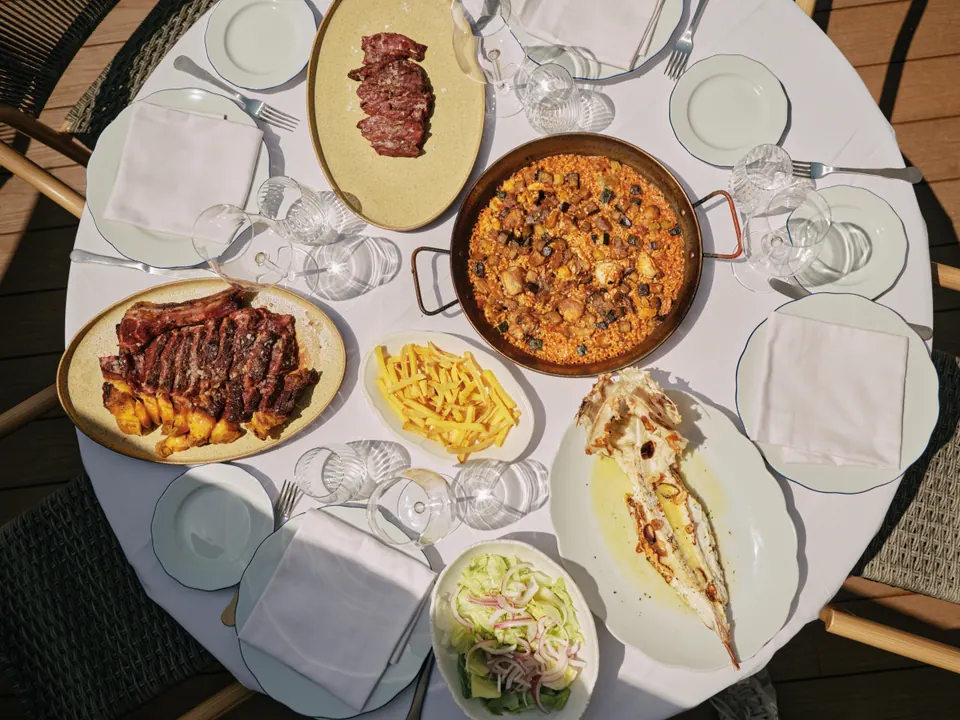 Mesa redonda con arroz, carnes, pescado y guarniciones en restaurante madrileño